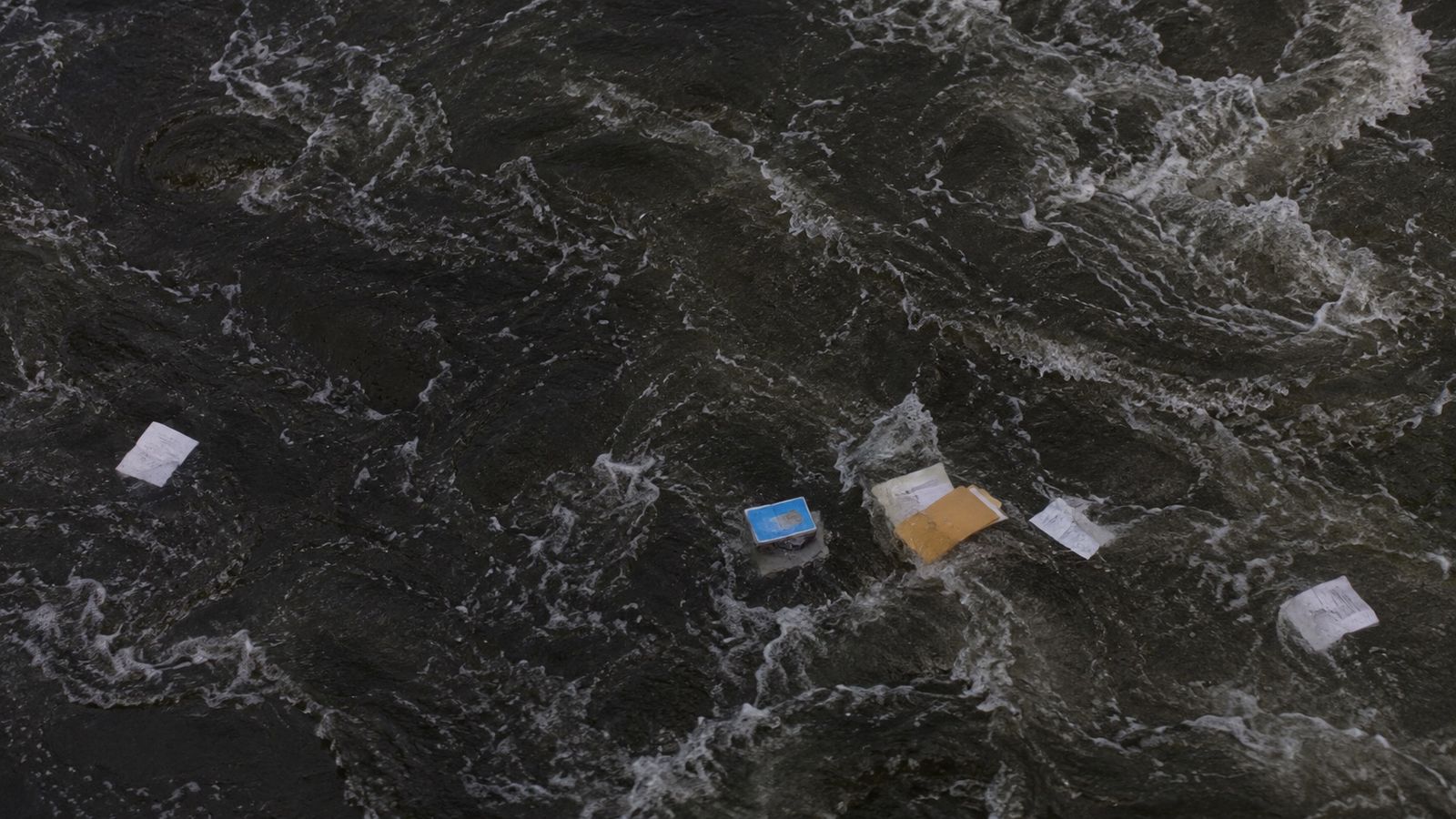 Claim documents and folders floating in rushing flood water